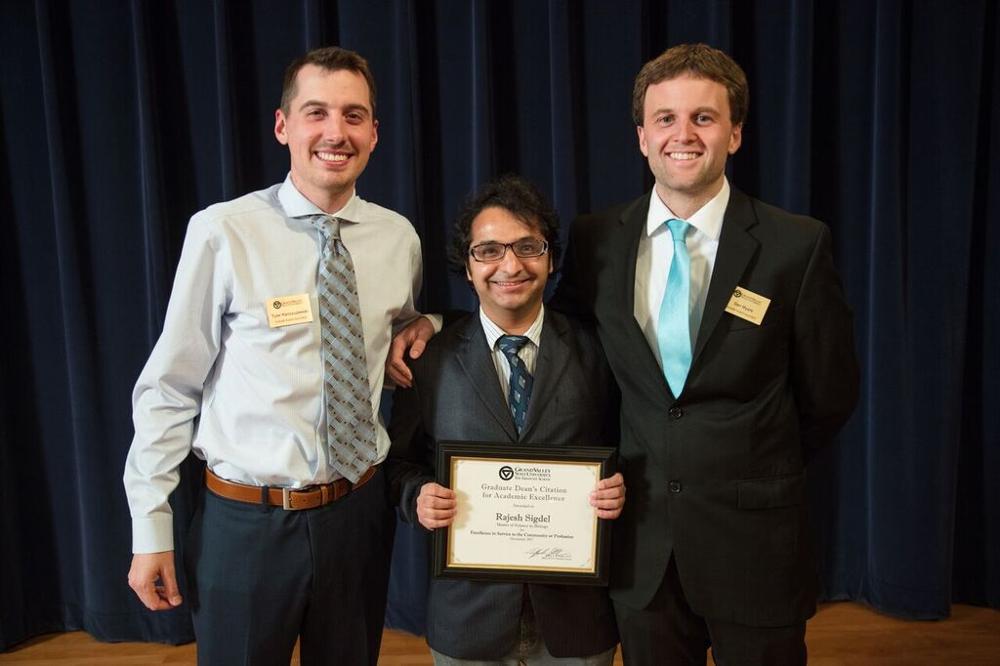 Award recipient is posing for a photo on stage with the GSA president and member